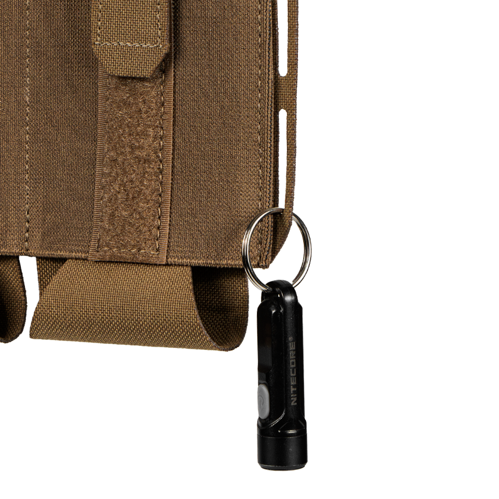 A small black flashlight on a keyring is attached to the brown fabric loop on the side of the Condor VAS Flex Placard tactical pouch.