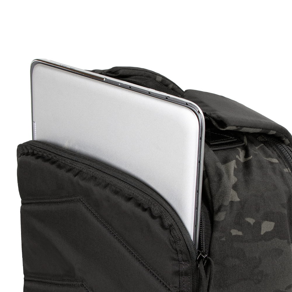 A silver laptop is partially tucked into the front compartment of the Condor Prime Pack 21L - MultiCam Black backpack.