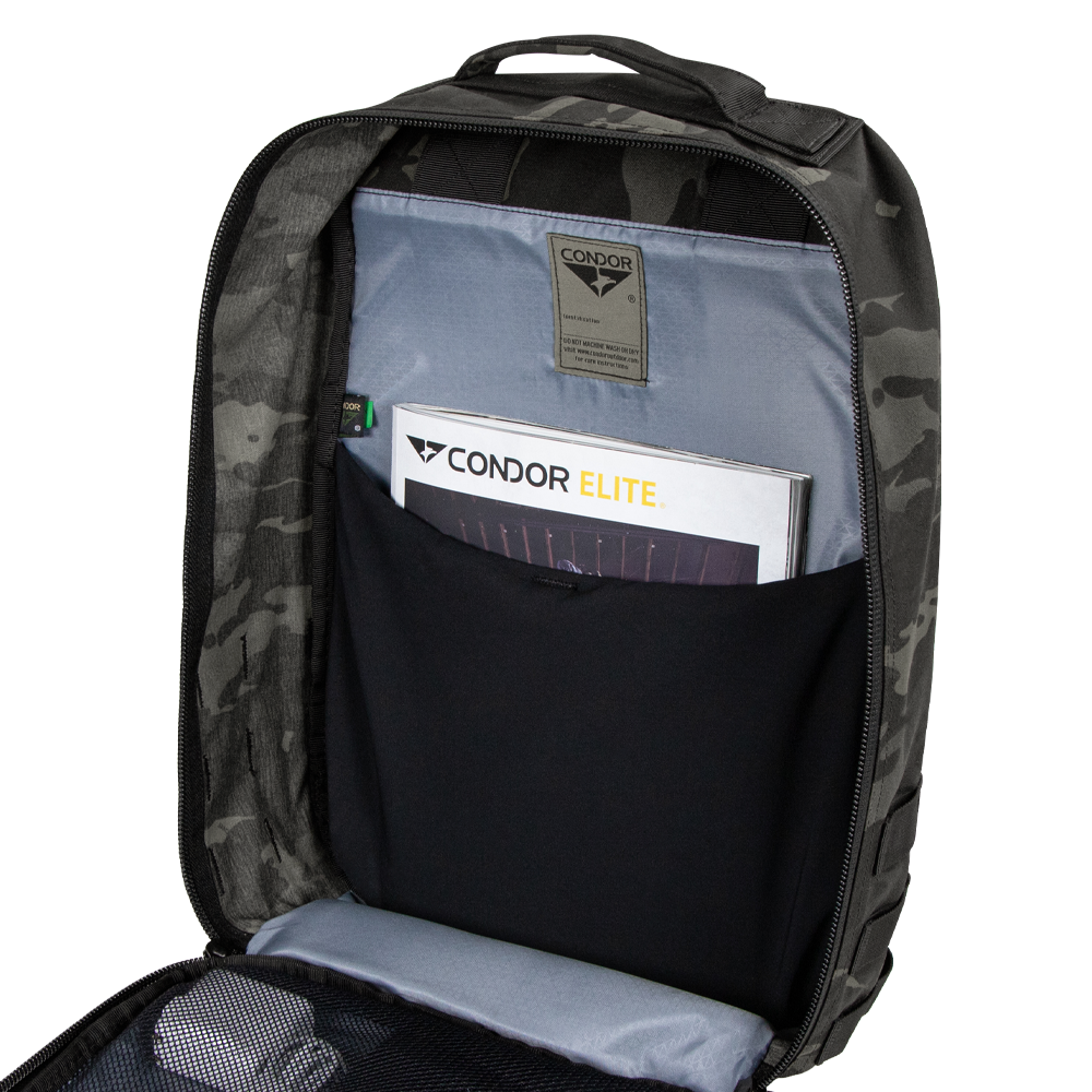 Open Condor Prime Pack 21L in MultiCam Black revealing an interior pocket with a Condor Elite booklet and a mesh zippered compartment.