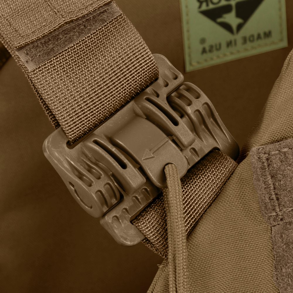 Close-up of a tan buckle fastener on a fabric strap, attached to brown material with visible stitching and a Made in USA label—part of the Condor Cyclone RS Plate Carrier, perfect for EDC or bushcraft gear.